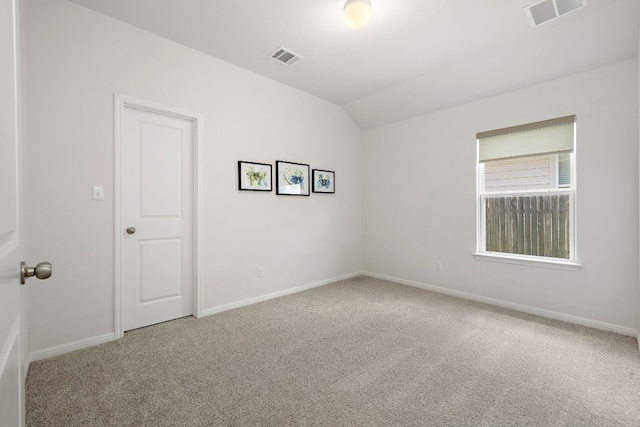 carpeted empty room featuring lofted ceiling, visible vents, and baseboards