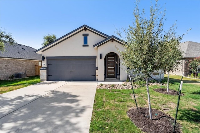 view of front facade featuring driveway, stucco siding, an attached garage, central air condition unit, and a front yard