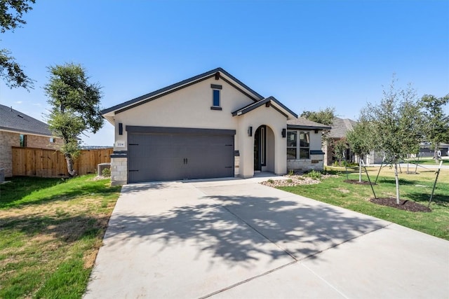 view of front of property with a front yard, concrete driveway, fence, and stucco siding