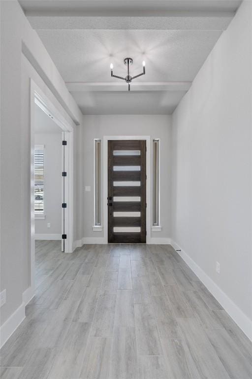 foyer featuring an inviting chandelier, light wood-style flooring, and baseboards