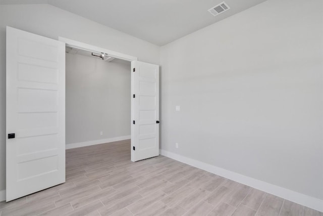 empty room with visible vents, light wood-style flooring, and baseboards