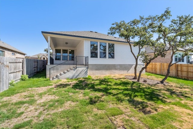 rear view of property with a yard and a fenced backyard