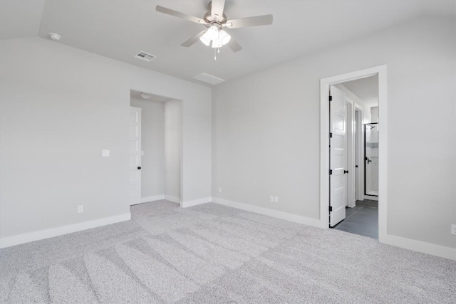 carpeted spare room with visible vents, baseboards, vaulted ceiling, and a ceiling fan