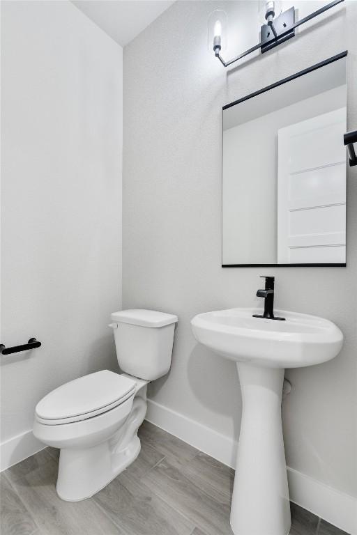 bathroom featuring wood finished floors, toilet, and baseboards