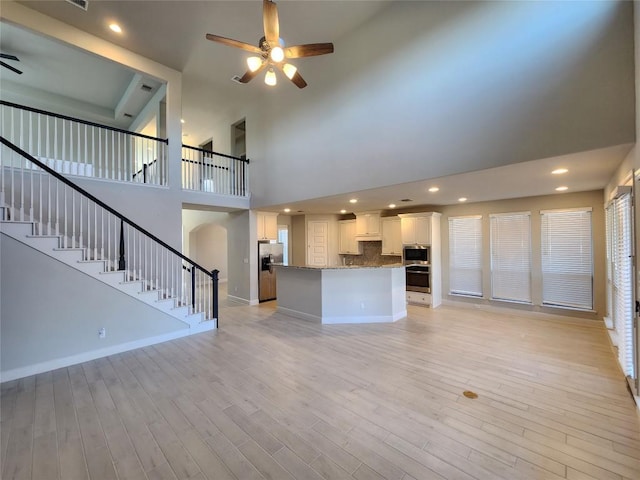 unfurnished living room with baseboards, light wood-style flooring, ceiling fan, stairway, and recessed lighting