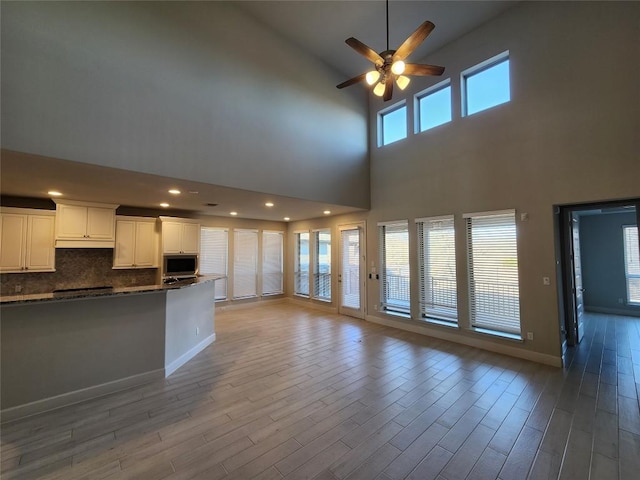 unfurnished living room featuring light wood-type flooring, ceiling fan, baseboards, and recessed lighting