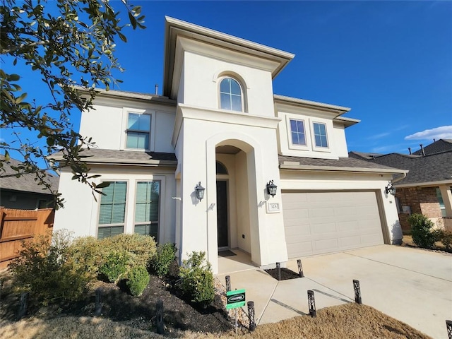 view of front of property featuring driveway, a garage, fence, and stucco siding