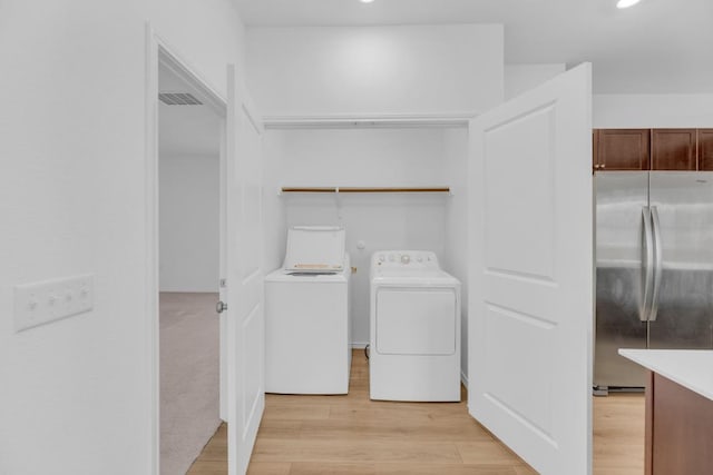 clothes washing area featuring laundry area, light wood-style floors, visible vents, and washer and dryer