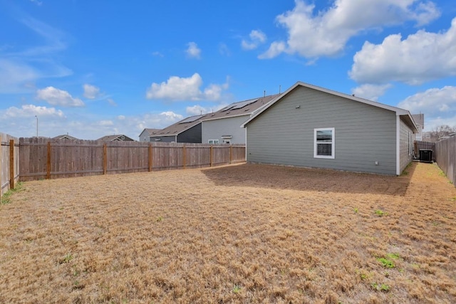 exterior space featuring a fenced backyard, central AC unit, and a yard