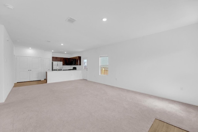 unfurnished living room featuring light carpet, visible vents, and recessed lighting