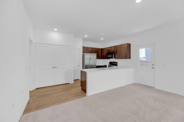 kitchen with black microwave, recessed lighting, a peninsula, light countertops, and freestanding refrigerator