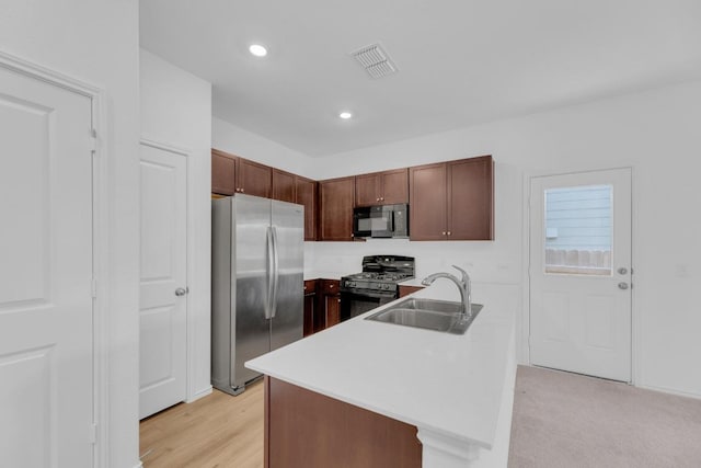 kitchen featuring visible vents, a peninsula, light countertops, black appliances, and a sink