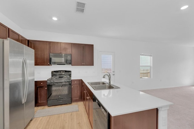 kitchen with light countertops, visible vents, a sink, a peninsula, and black appliances