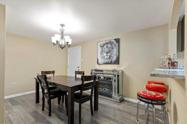 240 Riddle Rd, Cedar Creek, TX 78612 - dining space with wood finished floors, a chandelier, baseboards, and a dry bar
