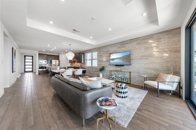 living room with a tray ceiling, wood finished floors, and a wealth of natural light