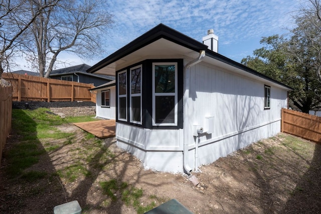 view of property exterior with a chimney and fence