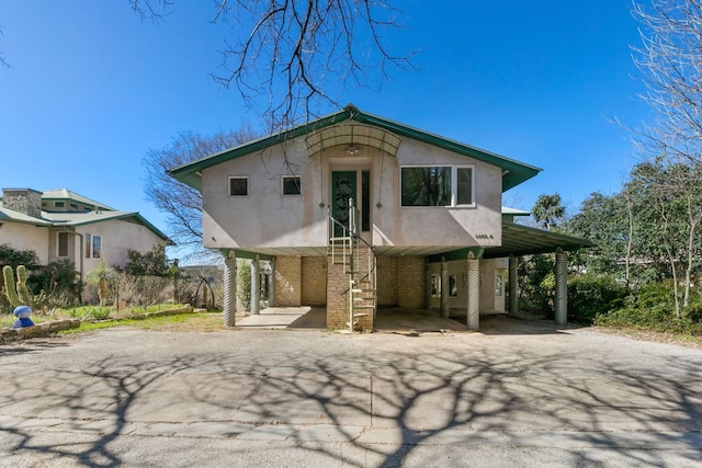 view of front of house with a carport, aphalt driveway, and stucco siding