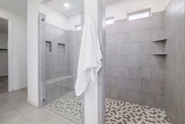 full bathroom featuring a spacious closet, tile patterned flooring, walk in shower, and baseboards