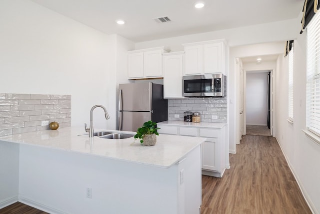 kitchen featuring visible vents, white cabinets, a sink, stainless steel appliances, and backsplash