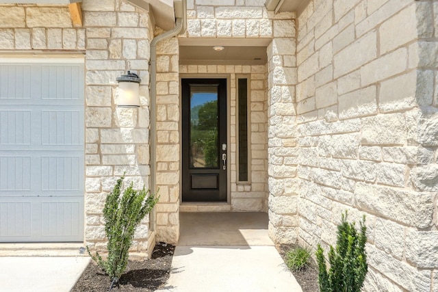 view of exterior entry with a garage and stone siding