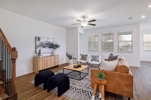 living room with visible vents, baseboards, ceiling fan, stairway, and wood finished floors