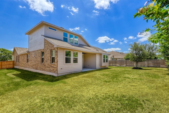 rear view of house featuring a yard, brick siding, and a fenced backyard