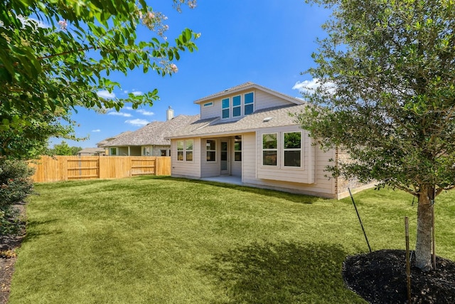 rear view of property featuring a patio, a lawn, and fence