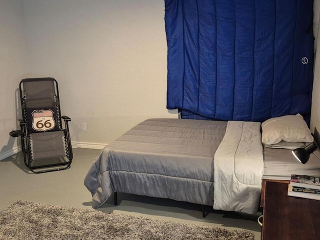 bedroom with baseboards and finished concrete flooring