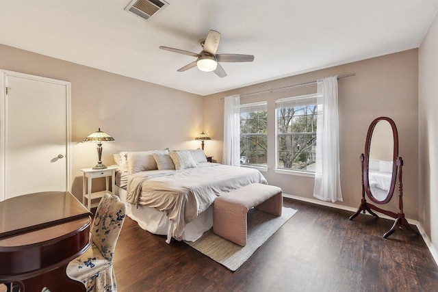 bedroom featuring a ceiling fan, dark wood-style flooring, visible vents, and baseboards