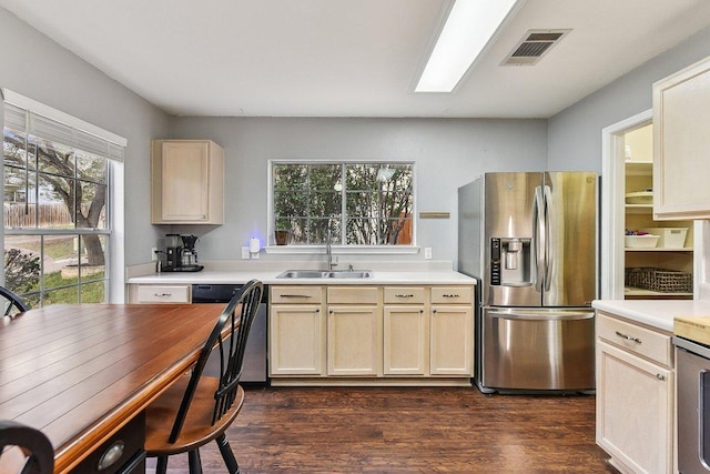 kitchen featuring stainless steel appliances, a sink, visible vents, light countertops, and dark wood finished floors