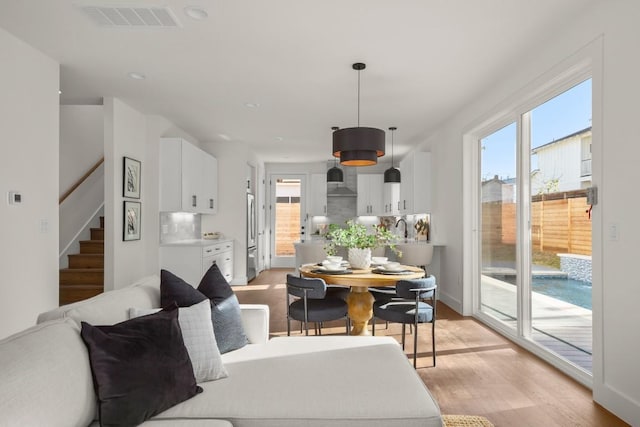 dining space with a wealth of natural light, visible vents, light wood-style flooring, and stairway