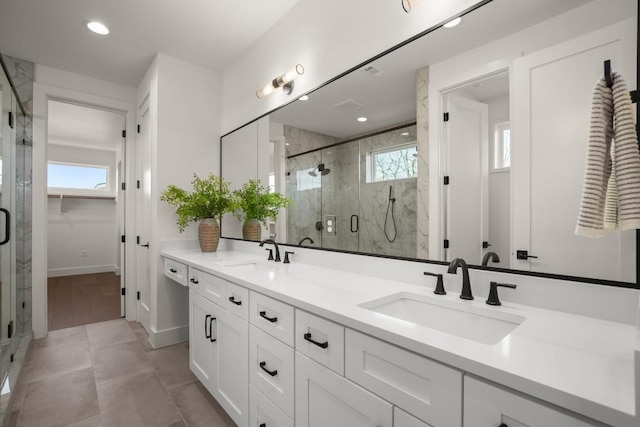 bathroom featuring a sink, a marble finish shower, and double vanity