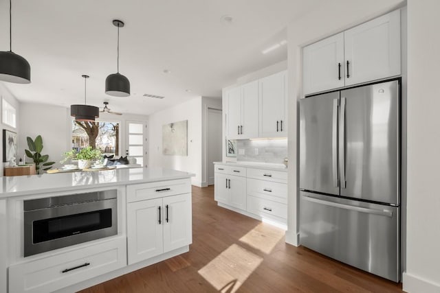 kitchen featuring backsplash, dark wood-style floors, stainless steel appliances, white cabinets, and light countertops