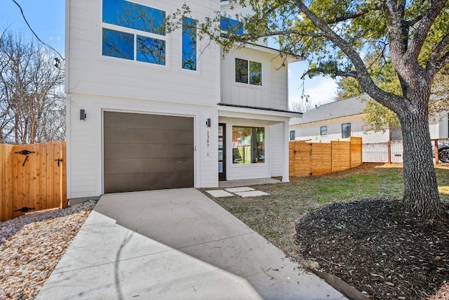 contemporary house with concrete driveway, fence, and board and batten siding