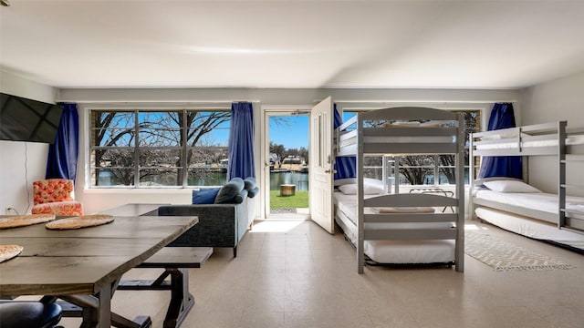 bedroom with multiple windows, tile patterned floors, and access to exterior