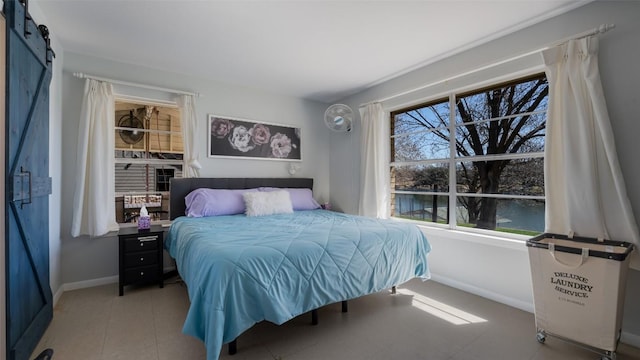 bedroom featuring light tile patterned floors, a barn door, and baseboards