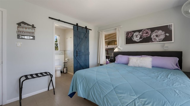 bedroom featuring connected bathroom and a barn door