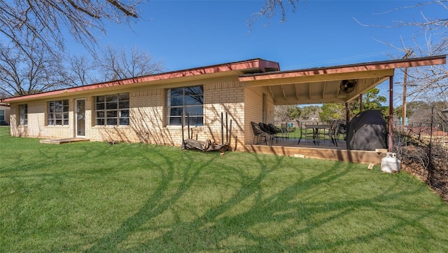 back of house featuring a patio, brick siding, and a lawn