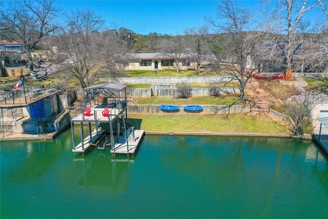 dock area featuring a water view, a lawn, and boat lift