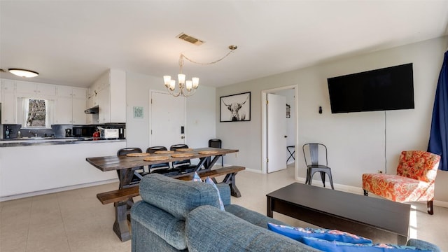 living room featuring light tile patterned floors, baseboards, visible vents, and a notable chandelier