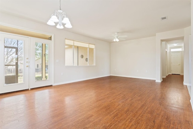 unfurnished living room with visible vents, ceiling fan with notable chandelier, wood finished floors, french doors, and baseboards