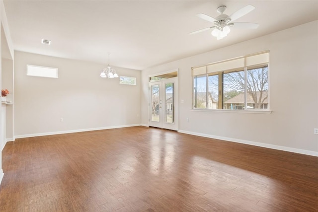 empty room featuring wood finished floors, visible vents, a wealth of natural light, and baseboards