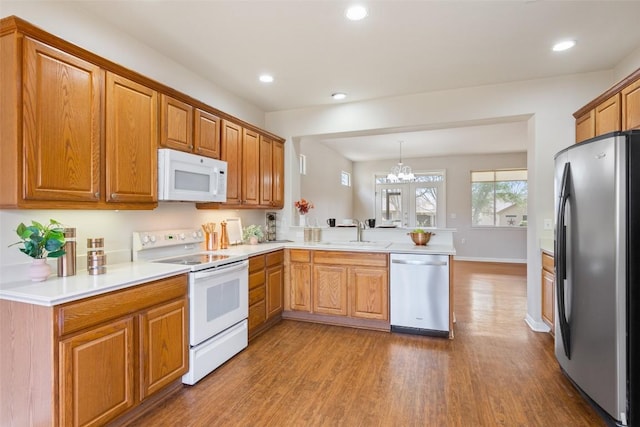 kitchen featuring dark wood-style floors, a peninsula, recessed lighting, a sink, and appliances with stainless steel finishes