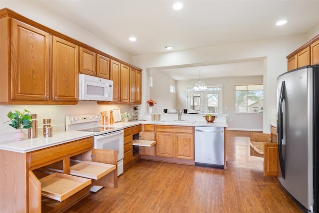 kitchen with a sink, wood finished floors, recessed lighting, stainless steel appliances, and a peninsula