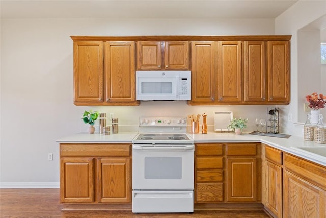 kitchen featuring brown cabinets, white appliances, light countertops, and wood finished floors