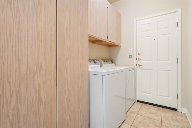 clothes washing area with light tile patterned floors, cabinet space, and washing machine and dryer