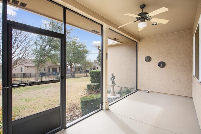 unfurnished sunroom featuring visible vents and a ceiling fan