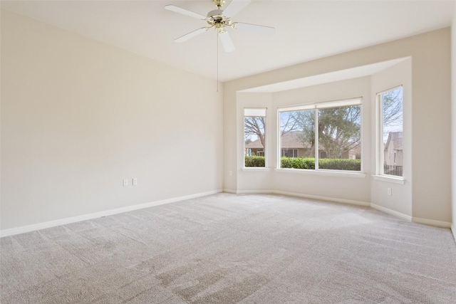 carpeted empty room with ceiling fan and baseboards