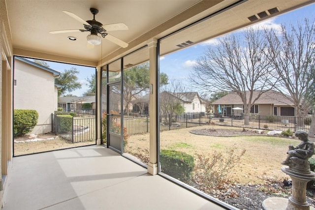 unfurnished sunroom featuring a residential view and a ceiling fan