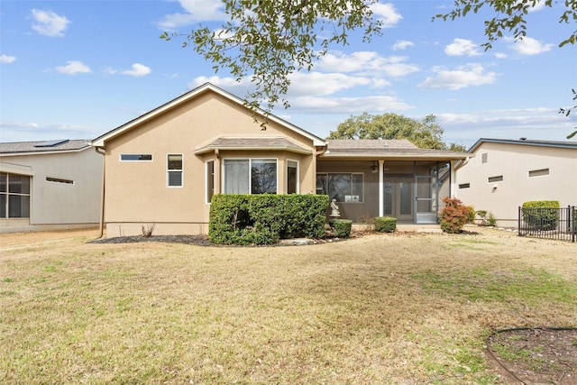 back of property with a yard, fence, stucco siding, and a sunroom